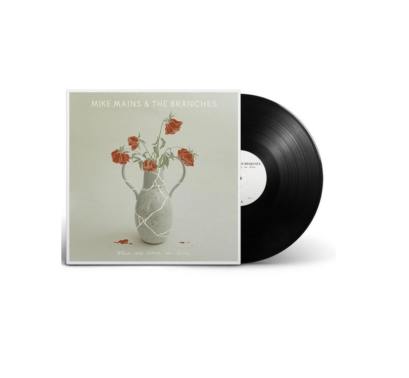 image of a black vinyl record on the right. album cover on the left. image of an album cover. at the top says mike mains & the branches. there is a cracked vace in the center, with illustrated red roses. at the bottom says when we were in love