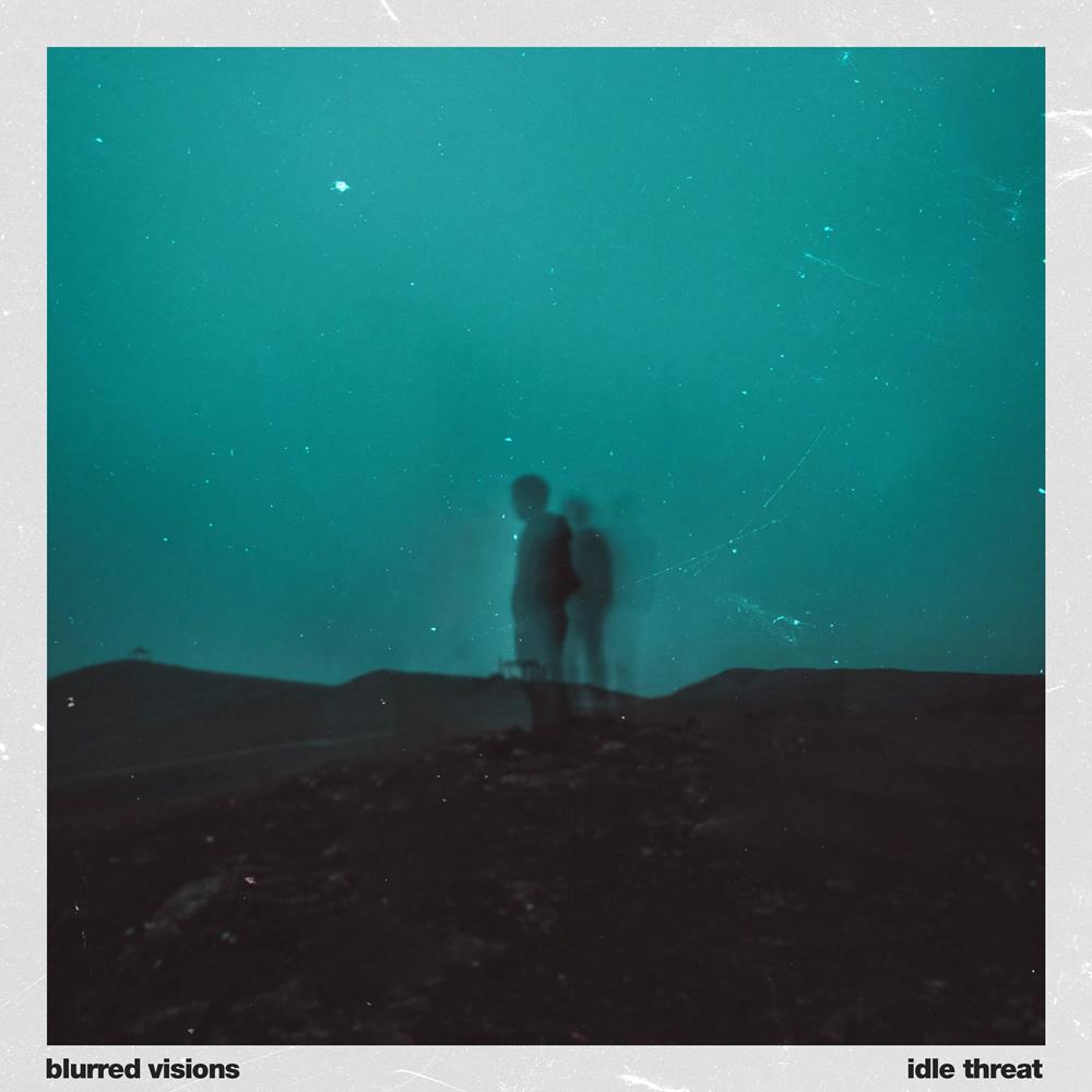 image of an album cover. cover is of two blurry people in the center, standing in a desert at night. the sky is teal. 