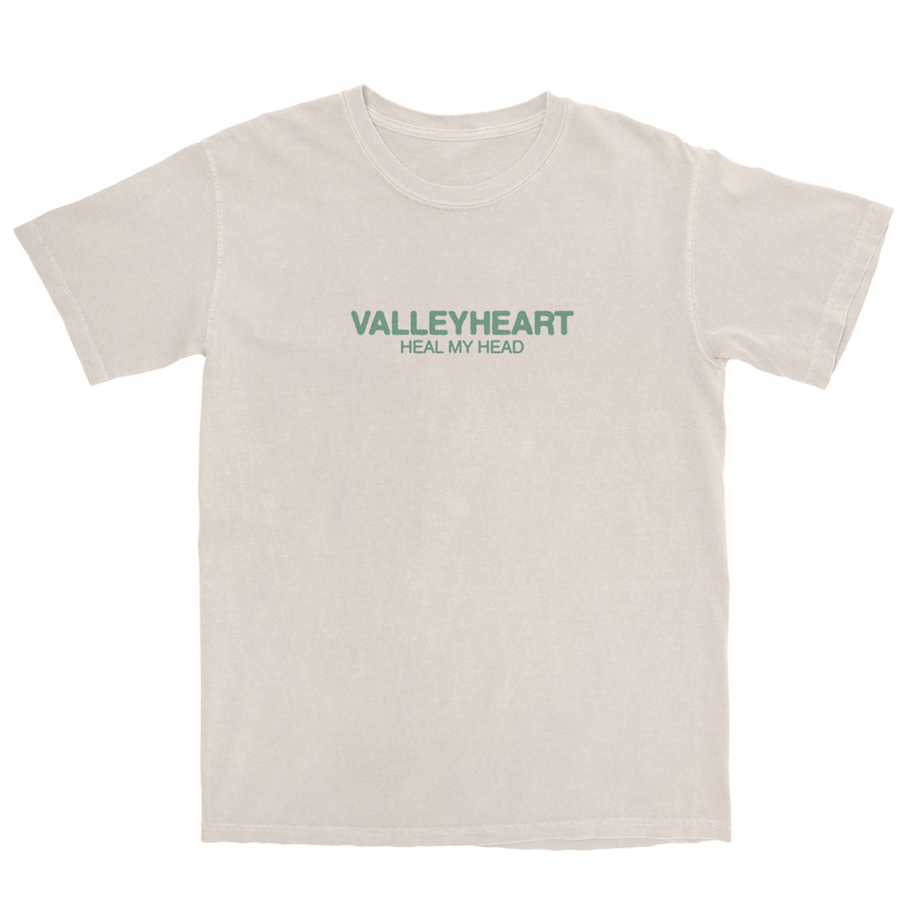 Image of cream colored Valleyheart tee lying flat on a white background. Front reads "Valleyheart Heal My Head" in green print. 