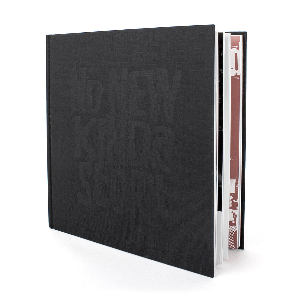 image of a black book on a white background. book is upright with the front cover open and the inside pages showing. the front of the book has black writing that says no new kind of story