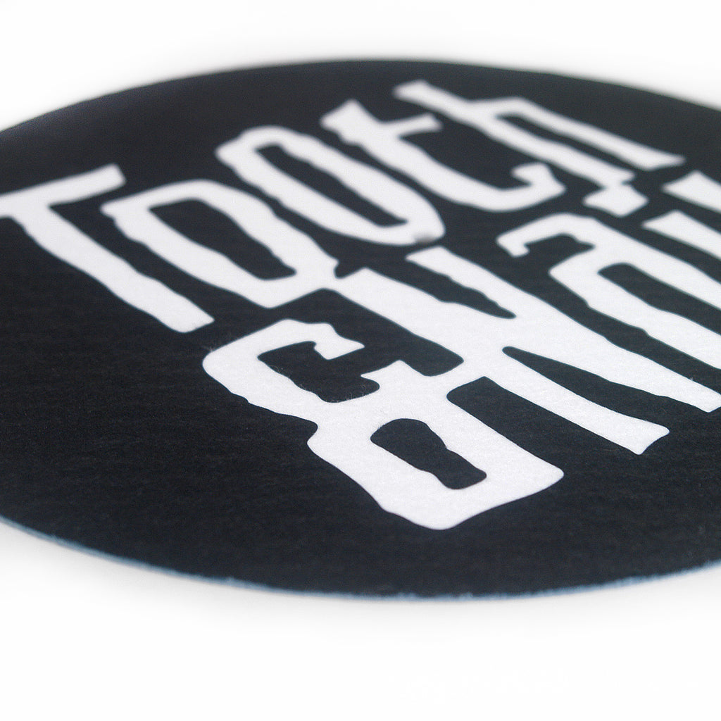 close up angled image of a black slipmat for a record player on a white background. slipmat is circular and has with text covering it that says Tooth & nail